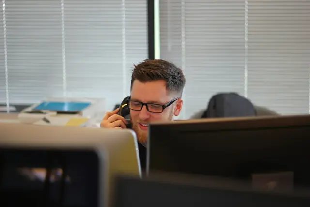 An accountant on the phone at a desk with two monitors