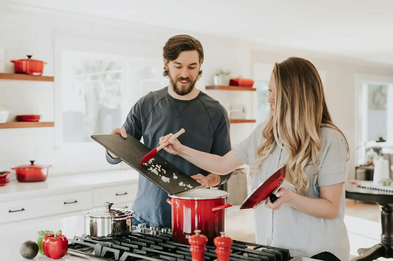 Two people cooking dinner together in a home kitchen, no laptop in sight