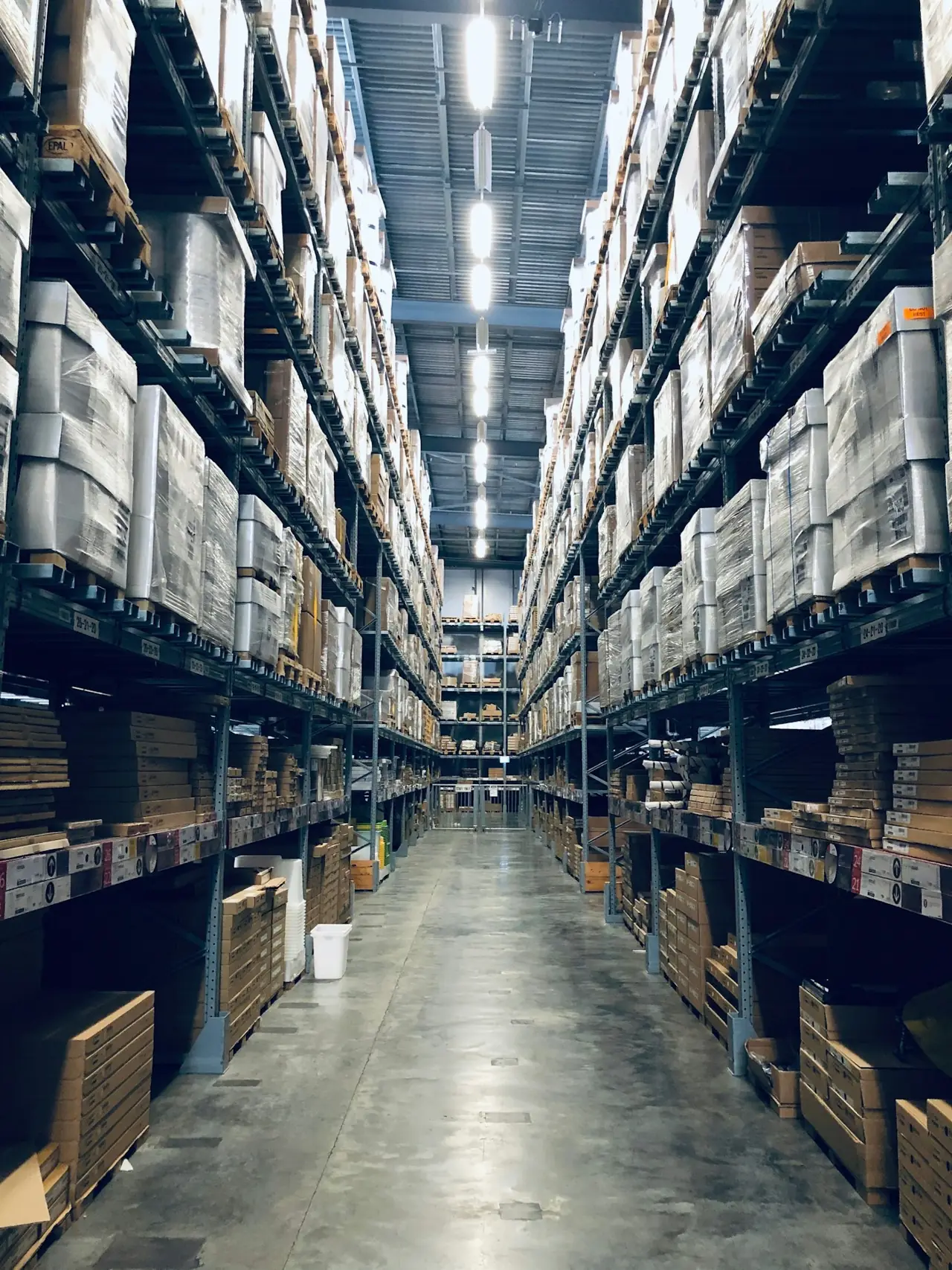 A tall warehouse aisle lined with stocked shelving